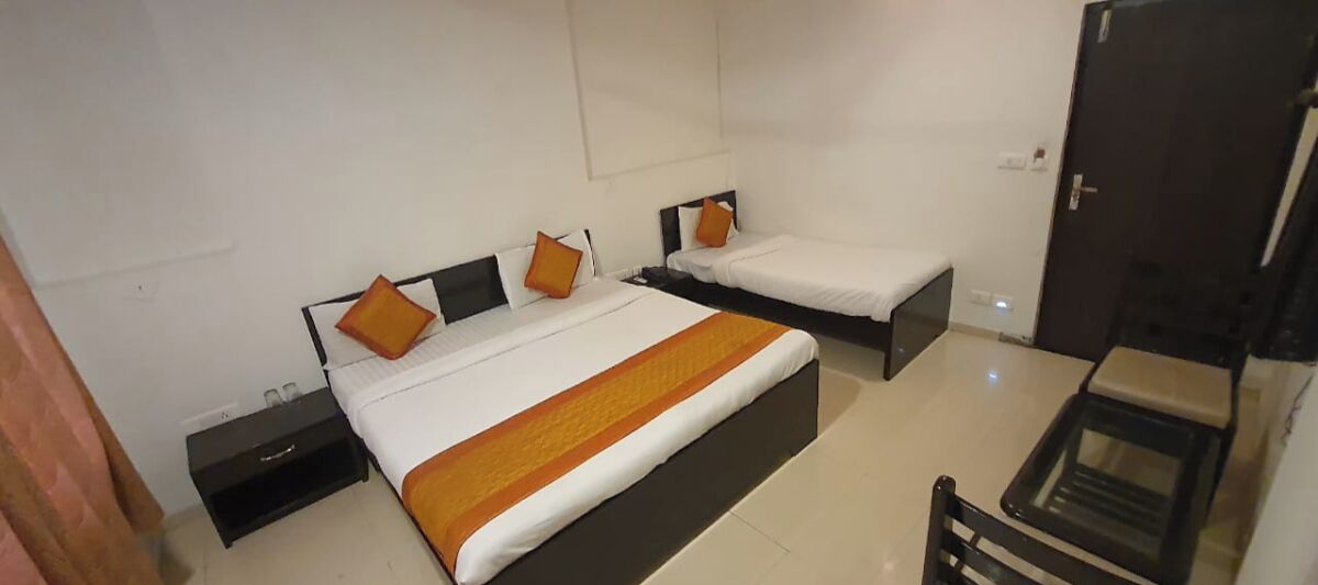A hotel room with two single beds, a small table, and a chair.