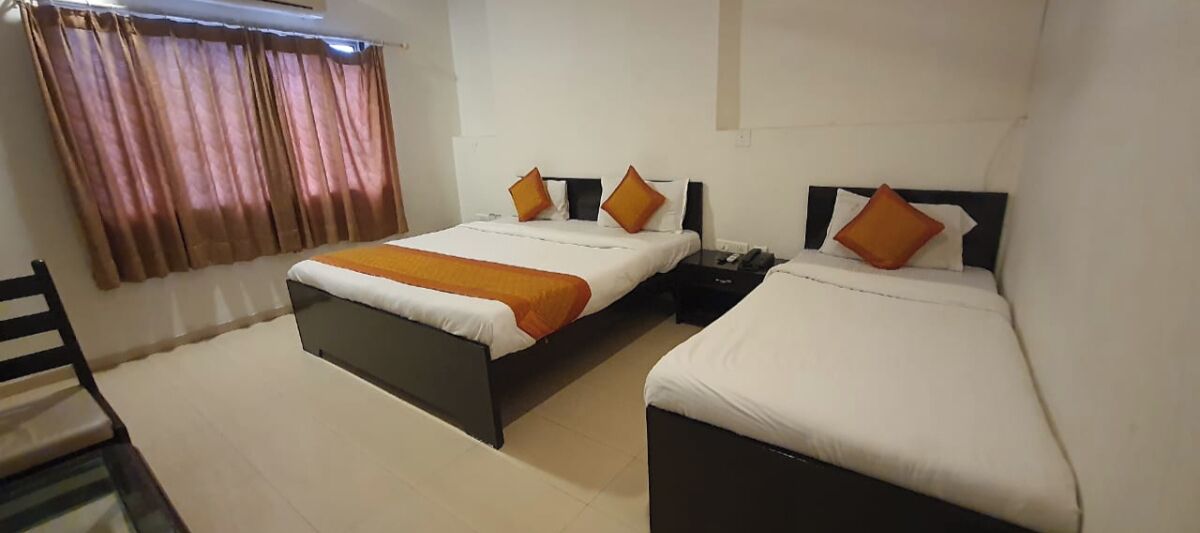 A hotel room with two single beds, a nightstand, a chair, and a window with curtains.