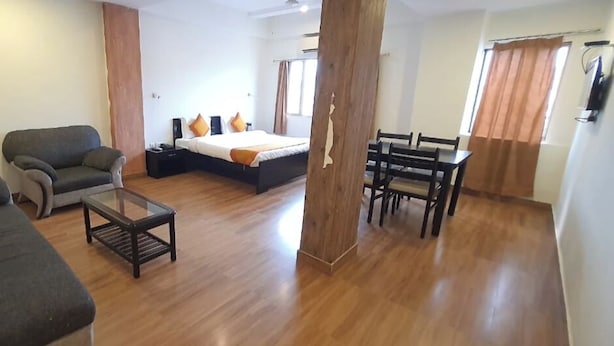 A spacious room with a large bed, a sofa, a small table, and a dining area. - Hotel Shree Vilas (Nathdwara)