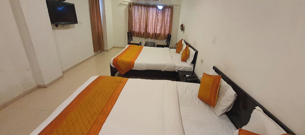 A hotel room with two beds, a TV, and a window with curtains.