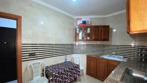 Una pequeña cocina con una mesa, dos sillas, un microondas y armarios de madera.