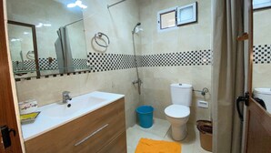 Un baño con lavamanos, espejo, inodoro, ducha y un salpicadero de azulejos a cuadros.