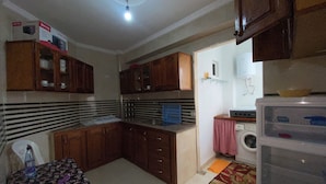 Una cocina compacta con armarios de madera, lavadora y una pequeña mesa con mantel floreado.