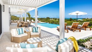 A covered outdoor area with a pool, lounge chairs, and a view of the ocean. - AMANERA "peaceful water" NEW Villa with Ocean View - Walk to Beach (The Bight Settlement)