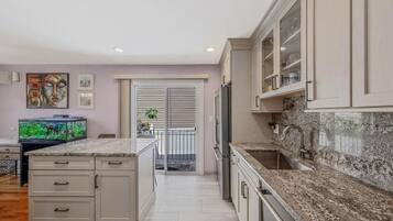 A modern kitchen with granite countertops, a built-in oven, and a stainless steel refrigerator.