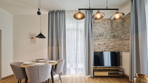 A modern dining area with a stone wall, wooden flooring, and a dining table set for four.