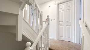 A staircase with white balusters and a beige carpet. - Kennedy 6 Bedroom 6 Bathrooms House in Hampton (Peterborough)