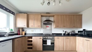 A modern kitchen with wooden cabinets, a built-in oven, a gas stove, and a window providing natural light. - Kennedy 6 Bedroom 6 Bathrooms House in Hampton (Peterborough)