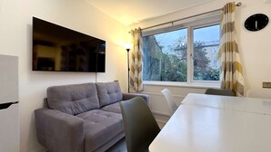 Un salon comprenant un canapé, une table à manger et un téléviseur fixé au mur.