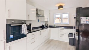 A modern kitchen with white cabinets, a black refrigerator, and a window with a view of the outside.