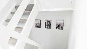 A white staircase leading to a gallery with three black and white cityscape photographs on the wall.