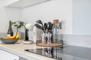 Een aanrecht met een fruitschaal, een koffiezetapparaat en een kruidenrek.