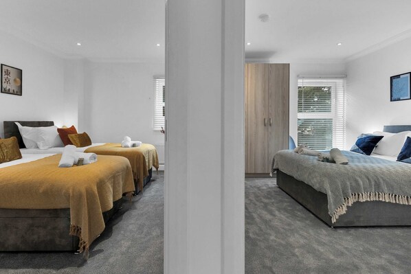 Een hotelkamer met twee bedden, een groot raam met zonwering en een kledingkast.