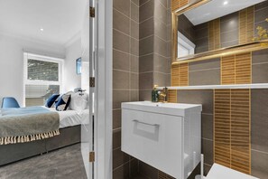 Een moderne slaapkamer met een bed, nachtkastje en een raam met zonwering.