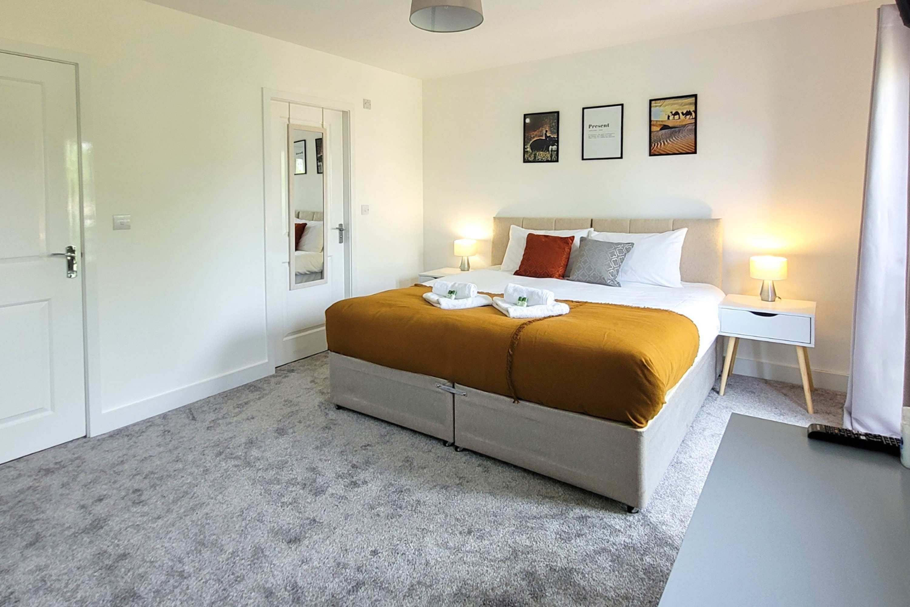 Een hotelkamer met een bed, nachtkastjes, een spiegel en kunst aan de muur.