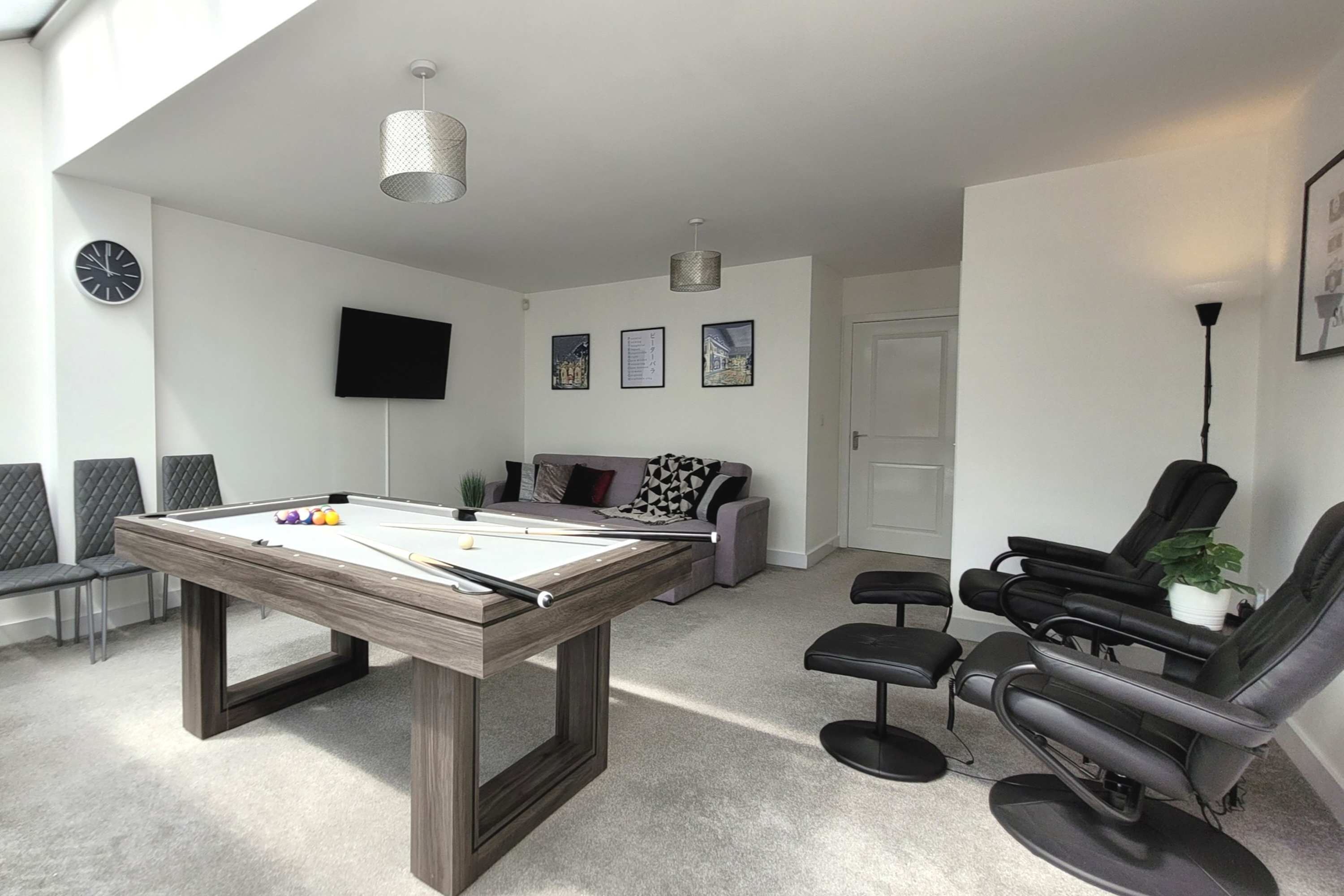 A modern living room with a pool table, a sofa, a TV, and a massage chair.