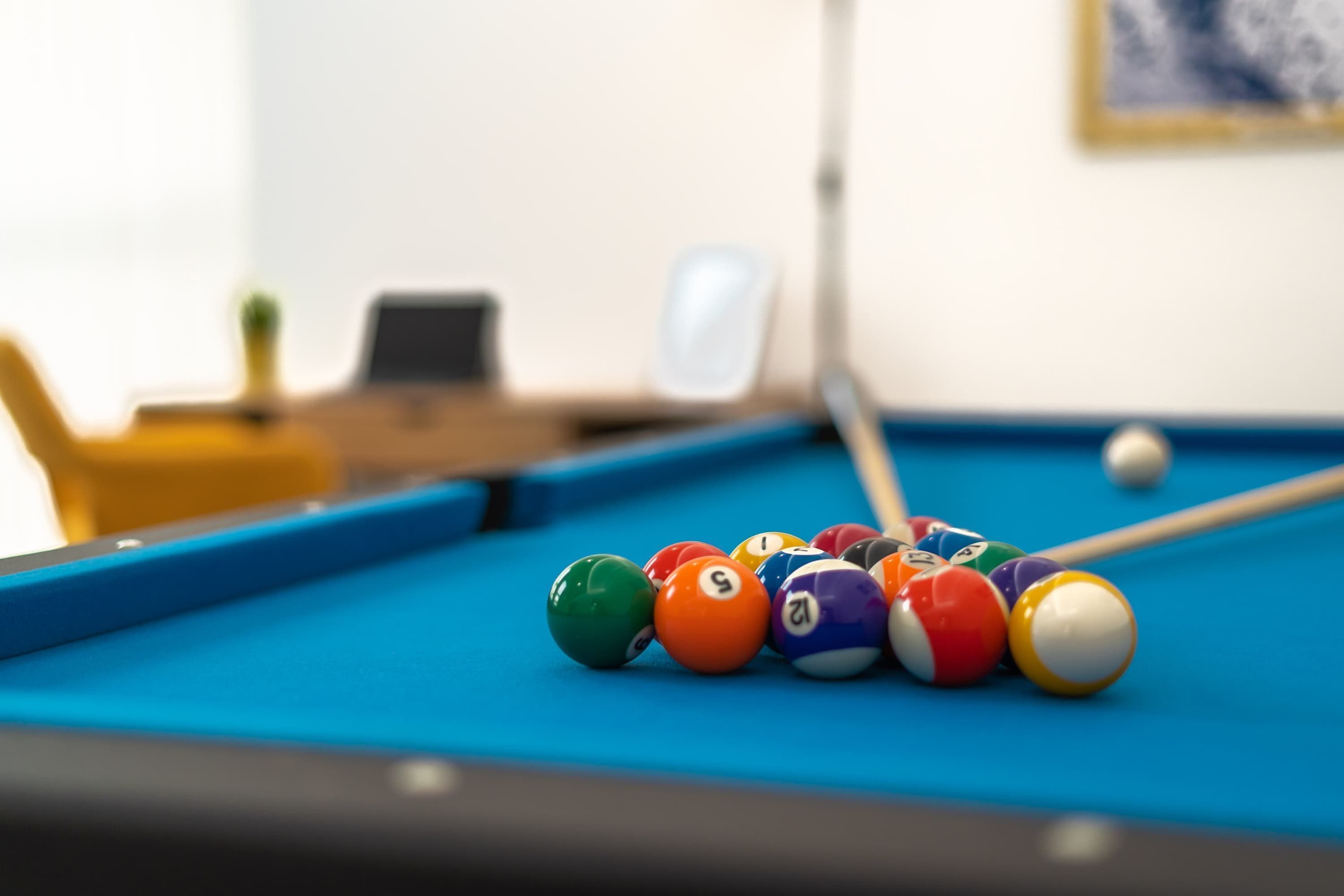 A pool table with colorful balls and a cue stick.