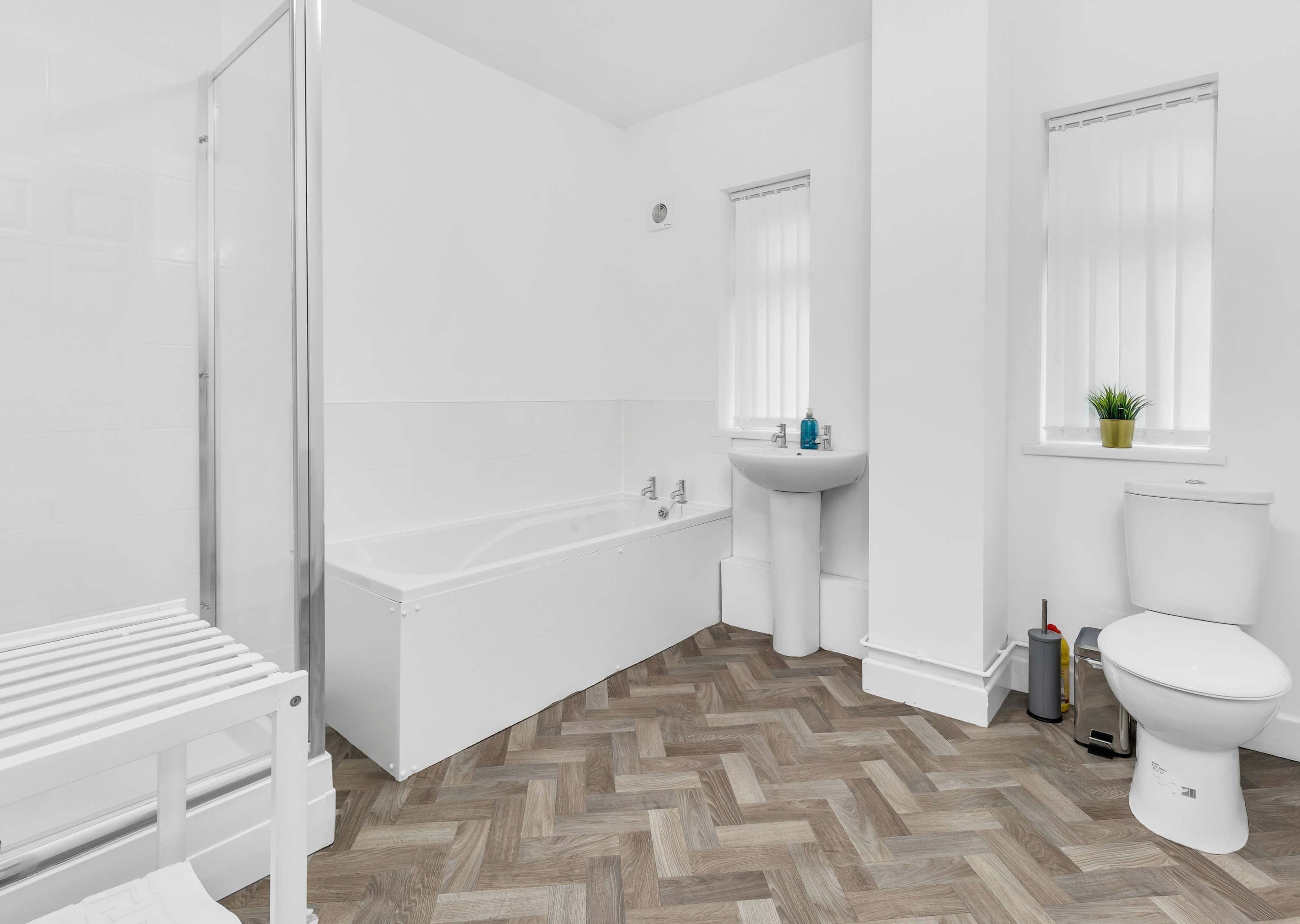 Ein modernes Badezimmer mit Badewanne, Waschbecken, Toilette und einem Fischgrätparkett.