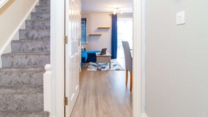 A hallway leading to a bedroom with a bed, a desk, and a chair.