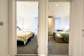 A bedroom with two beds, a wardrobe, and a carpeted floor.