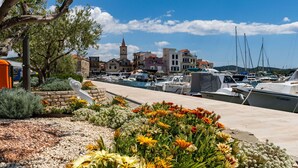 Un puerto deportivo con barcos amarrados, una iglesia con torre y un muro de piedra con flores.
