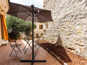 A patio with a table and chairs, a large umbrella, and a stone wall. - Stunning  villa for 3 guests with WIFI, A/C, TV and balcony (Pompeiana)