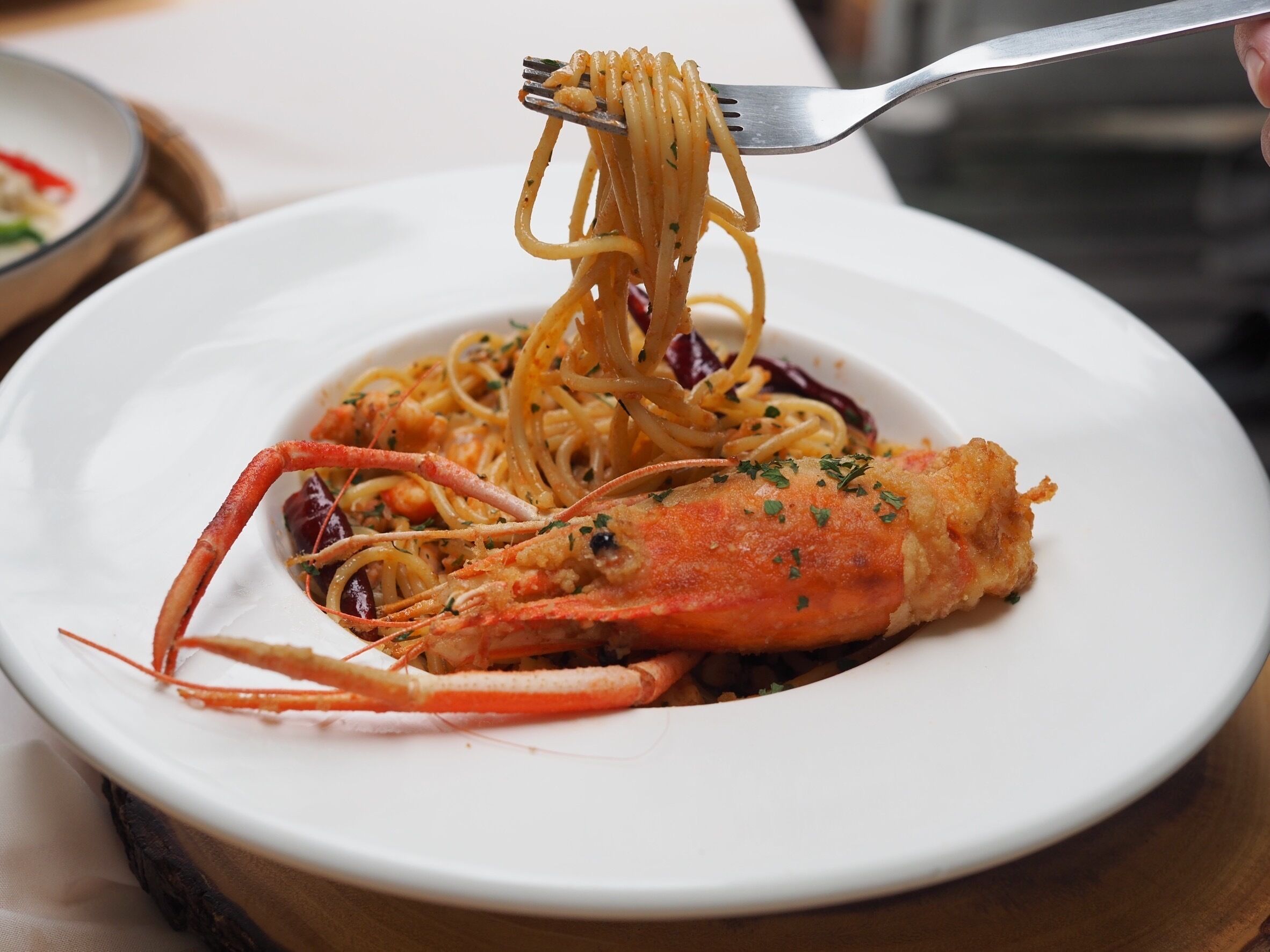 En tallrik spaghetti med en hummermusling på en vit tallrik.