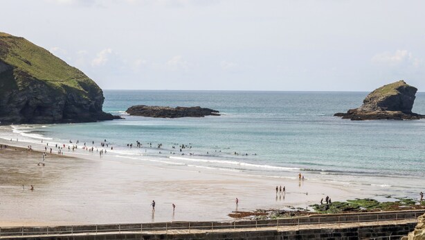 A beach with rocky outcrops, clear blue water, and a sandy shore. - Folly View (Redruth)