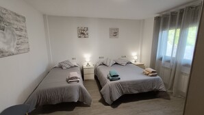 A twin room with two beds, bedside tables with lamps, a window with curtains, and artwork on the walls. - OASIS INN PEDORNES.A retreat between sea & mountains on Galicia’s Atlantic coast (Pedornes)
