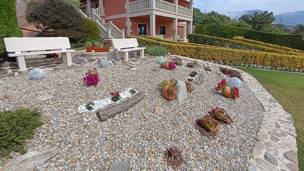 A two-story building with a balcony, surrounded by a landscaped garden with pebbles, flowers, and a bench. - OASIS INN PEDORNES.A retreat between sea & mountains on Galicia’s Atlantic coast (Pedornes)