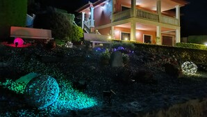 A two-story building with a balcony, surrounded by landscaped gardens and decorative lighting. - OASIS INN PEDORNES.A retreat between sea & mountains on Galicia’s Atlantic coast (Pedornes)