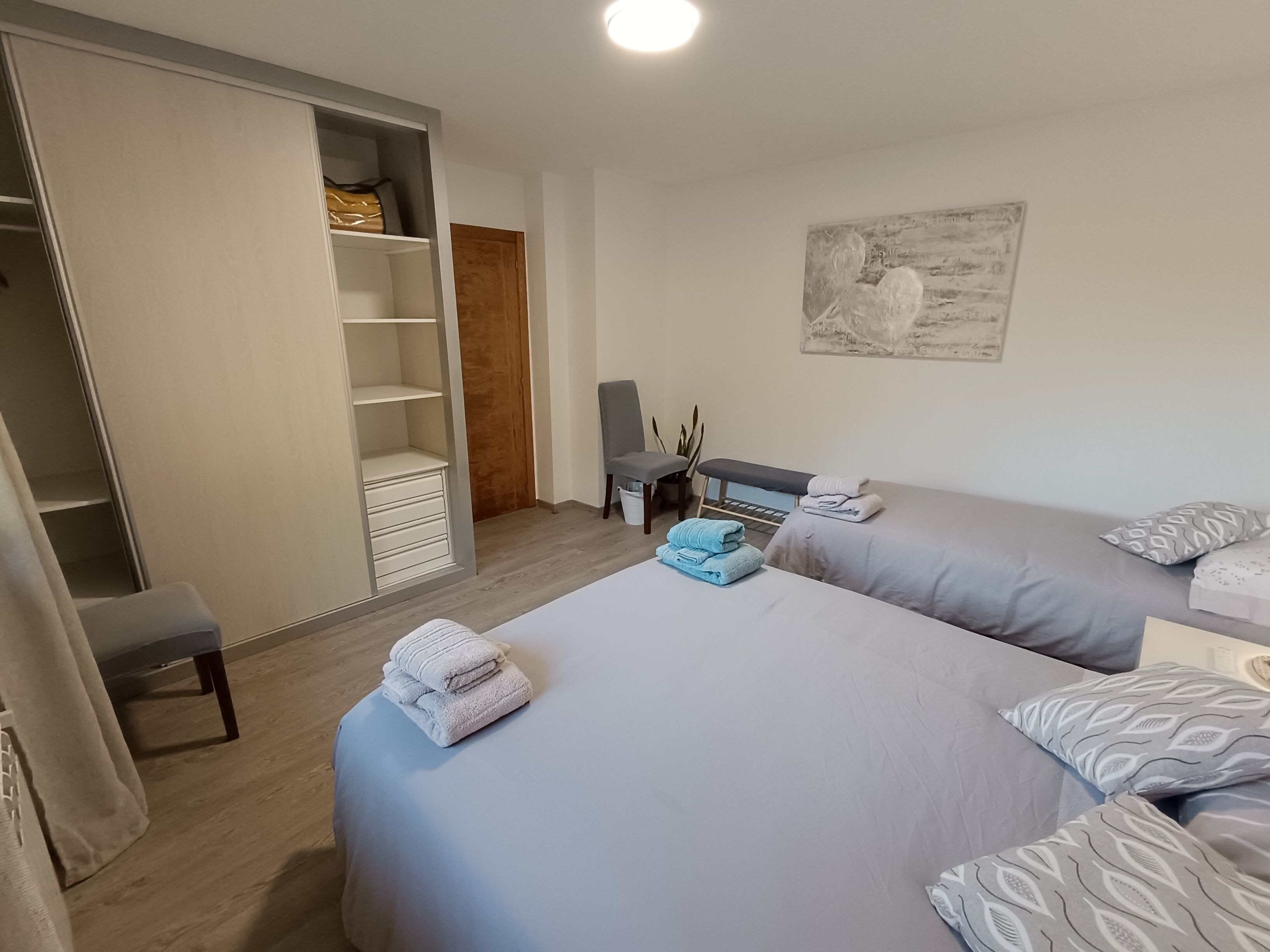 Un dormitorio con dos camas, un escritorio, una silla, un armario y una puerta.