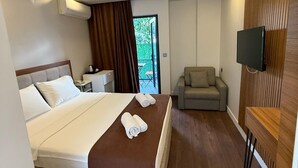 Una habitación de hotel moderna con una cama grande, un sofá, un televisor y vistas al exterior.