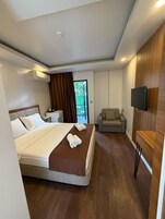 Una habitación de hotel moderna con una cama grande, un sofá, un televisor y vistas al exterior.