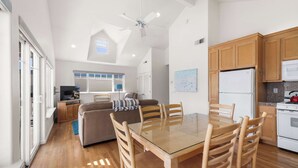 A spacious living area with a glass-top dining table surrounded by wooden chairs, a sofa, and a television in the background. - Capitola Sea Winds one block to Capitola Beach (Capitola)
