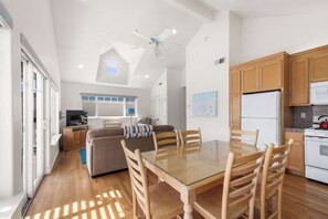 A spacious living area with a glass-top dining table surrounded by wooden chairs, a sofa, and a television in the background. - Capitola Sea Winds one block to Capitola Beach (Capitola)