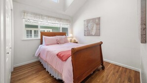 A bedroom with a wooden bed, white walls, a window with shutters, and a wall-mounted artwork. - Capitola Sea Winds one block to Capitola Beach (Capitola)