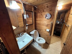 Ett badrum med träpanel på väggarna, utrustat med handfat, toalett och en spegel.