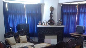 A living room with a sofa set, a coffee table, and a fireplace. - Majestic Cottage with WiFi in Bhimtal (Ghorakhal)