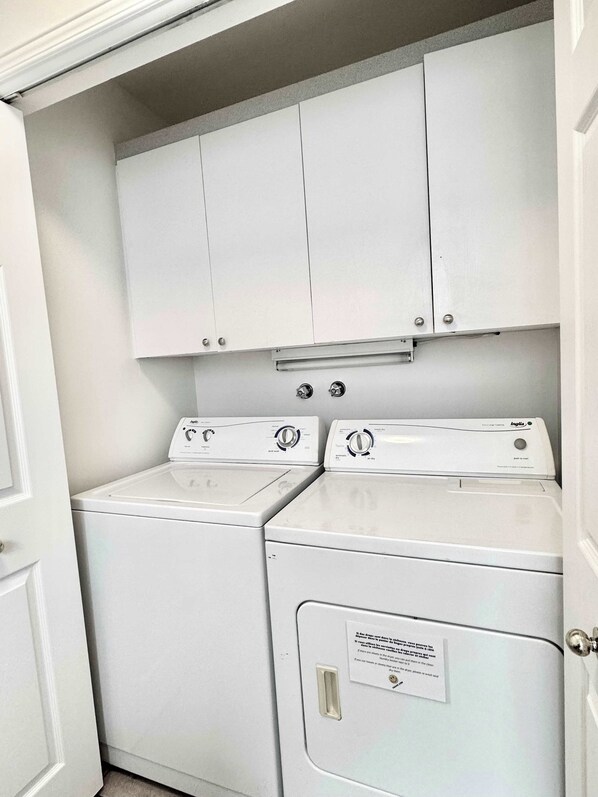 A laundry room with two front-loading washing machines and a cabinet above them.