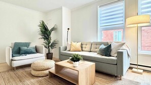 Un salon moderne avec un canapé gris, une petite table basse et un lampadaire.