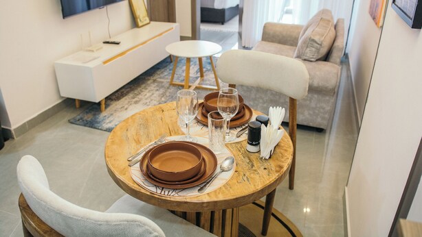 Un comedor con una mesa redonda para dos personas, un sofá y un televisor montado en la pared.