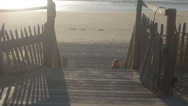 A wooden boardwalk leading to a beach with a fence on either side. - Le Cosy Zen des Sables (Mimizan)