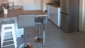 A modern kitchen with a central island, stainless steel appliances, and pendant lighting. - Le Cosy Zen des Sables (Mimizan)