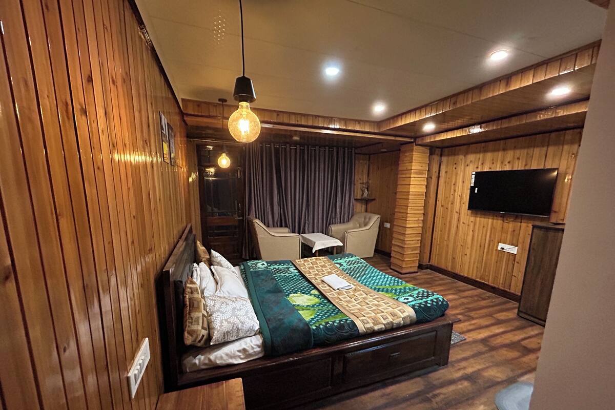 A bedroom with a bed, bedside tables, a TV, and a wooden wall panel.