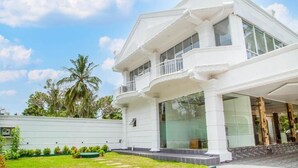 Um edifício branco com várias varandas e grandes janelas.