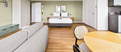 Una habitación de hotel moderna con cama, sofá, mesa de comedor y área de cocina.