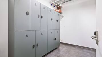 A row of grey lockers numbered 1 to 10, with a ventilation system above and a wall-mounted sensor on the right.