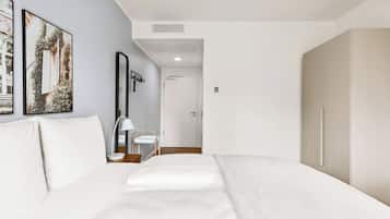 A modern hotel room with a large bed, a bedside table, a lamp, and a wardrobe.