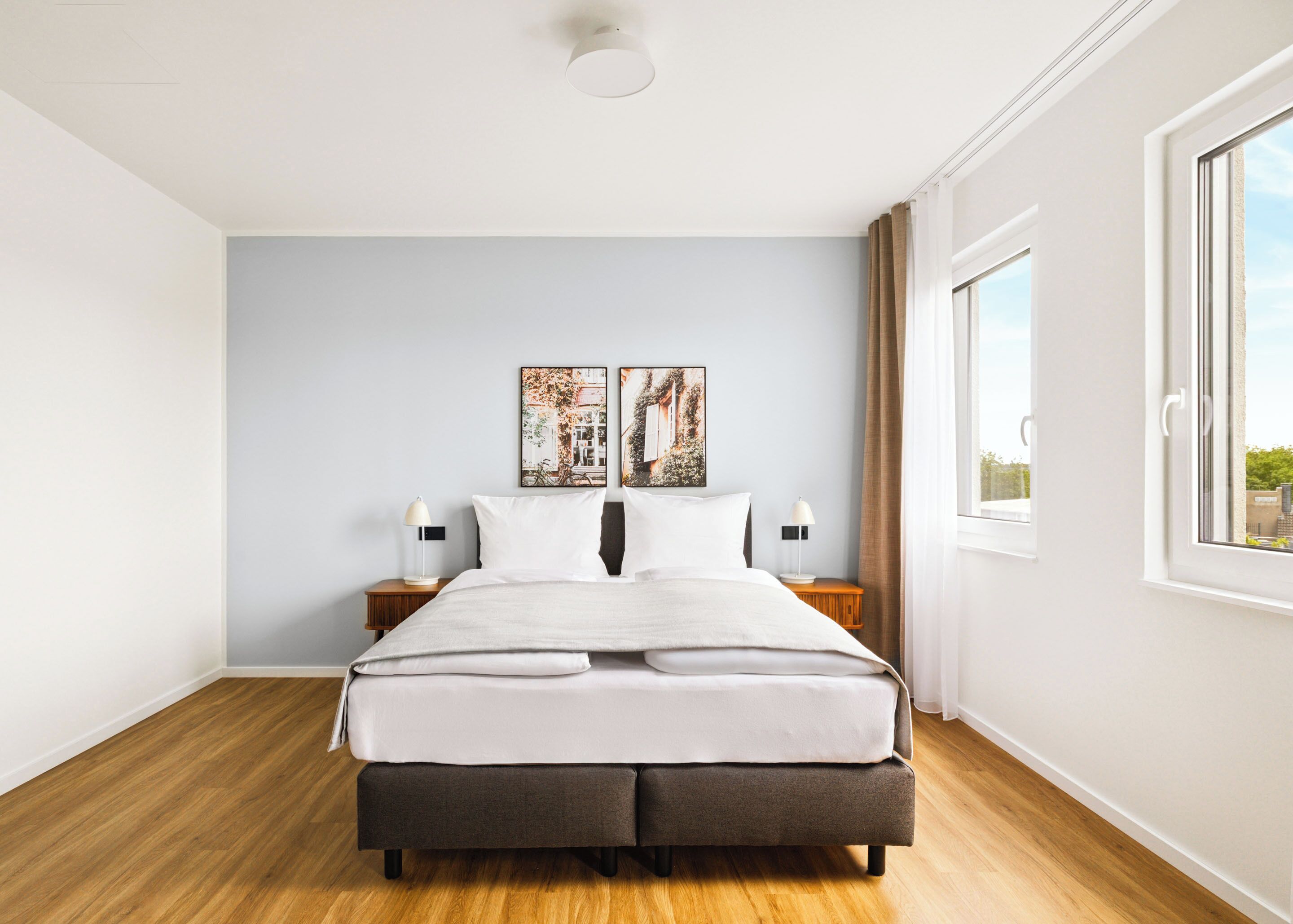 Een moderne slaapkamer met een groot bed, twee nachtkastjes en uitzicht op de stad.